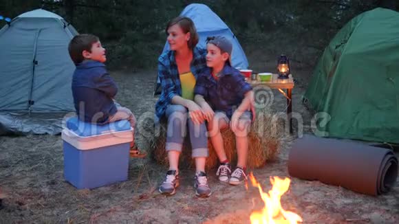 在背景帐篷和树木中的年轻家庭在森林中的家庭周末母亲和两个孩子坐在一起视频的预览图