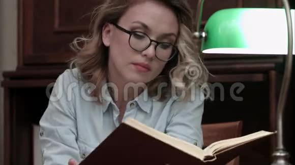 戴眼镜的严肃年轻女子在书中寻找信息视频的预览图
