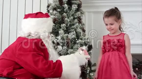 圣诞老人送礼物给一个惊讶的小女孩拥抱她视频的预览图