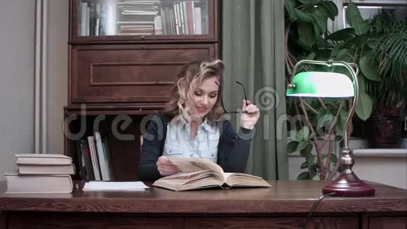 微笑着的年轻女子一边在书中寻找信息一边高兴地点头视频的预览图