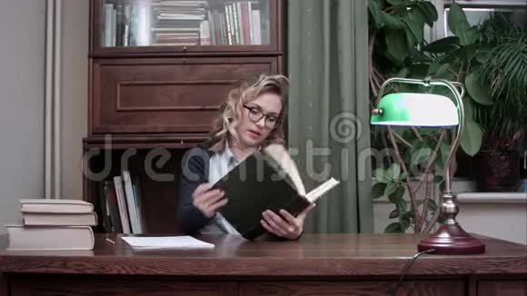 一位戴着眼镜的年轻女子在书房的桌子旁探索这本书视频的预览图