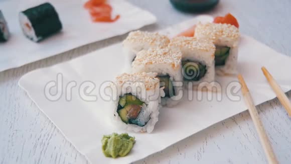 筷子从盘子里取出寿司卷在日本餐馆里蘸酱油慢动作视频的预览图
