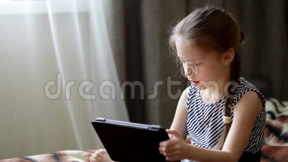 可爱的小女孩在平板电脑里玩视频的预览图