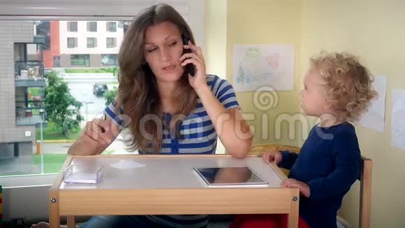妈妈打电话帮小女孩玩平板电脑商业妇女工作视频的预览图