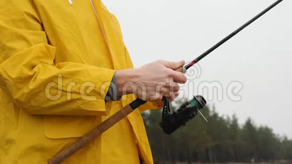 把穿黄色雨衣的渔夫关起来旋转着鱼卷慢动作视频的预览图