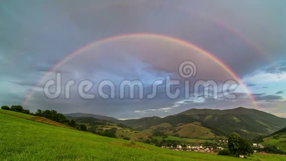 双彩虹覆盖绿色草地和乡村景观与云天时光流逝视频的预览图