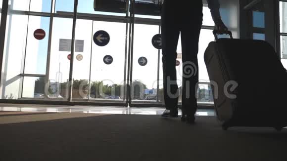商人带着行李从机场走出来一个人穿过玻璃自动门来到大街上翻滚视频的预览图