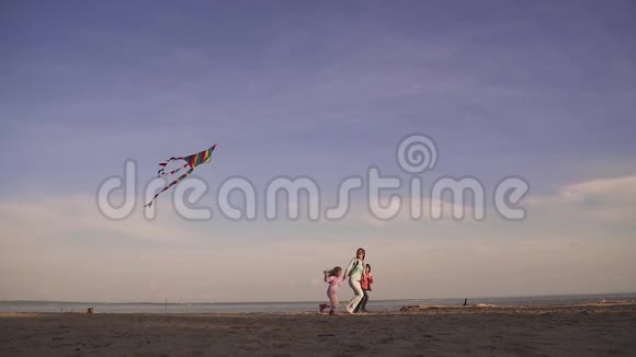 妈妈和孩子们一起在海上日落时在户外玩一家人放风筝快乐的春天视频的预览图
