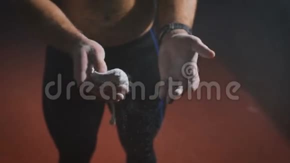 肌肉发达的运动员把镁砂粉涂在手掌上然后去健身房训练视频的预览图
