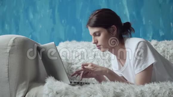 在家里躺在沙发上用笔记本电脑的女人视频的预览图