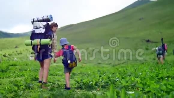 母亲和她的儿子背着徒步旅行背包在青山绿水中行走视频的预览图