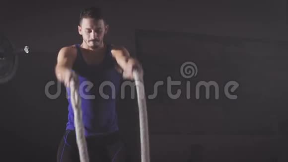 穿着蓝色衬衫的交叉式男子在健身房里做强力扣绳运动视频的预览图
