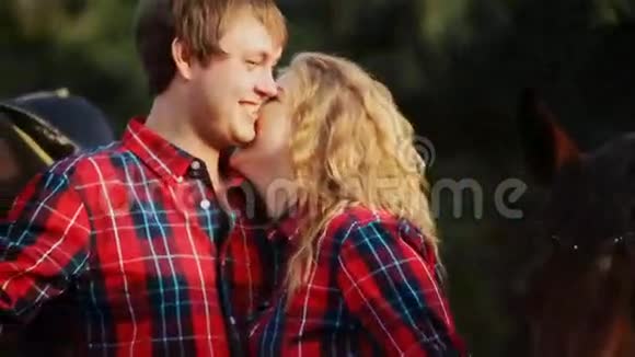 快乐的一对情侣在马周围散步时接吻视频的预览图