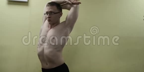 在健身前伸展手臂健身强男运动员站立室内热身视频的预览图