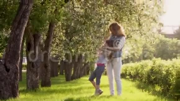 母亲在一个苹果园里拥抱女儿母亲和女儿沿着苹果树的林荫道散步儿童和儿童视频的预览图