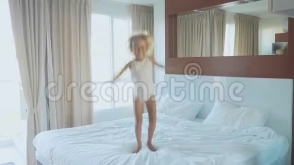 早晨小女孩在卧室里慢动作地跳上床视频的预览图