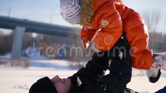 男人在阳光明媚的冬天和你的孩子玩抱在怀里冬季景观视频的预览图