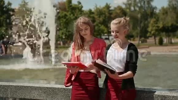 学院的年轻女学生一起在喷泉附近的公园里阳光灿烂视频的预览图