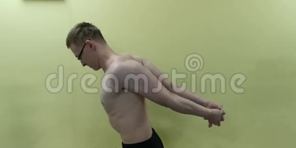 在健身前伸展手臂健身强男运动员站立室内热身视频的预览图