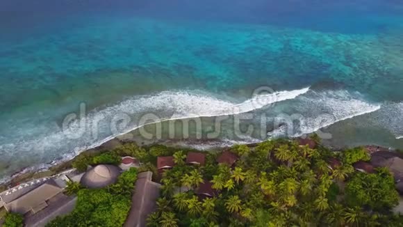 在马尔代夫有白沙棕榈树和绿松石印度洋的热带岛屿度假酒店的空中景色巨大的海浪视频的预览图
