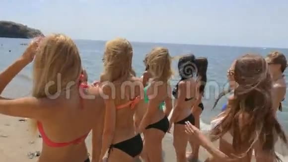 一群穿着比基尼的漂亮模特沿着海滩的海岸跑视频的预览图