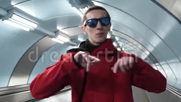 年轻男子穿着红色夹克和太阳镜站在自动扶梯上狂吠视频的预览图