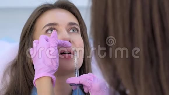 美容师在女性嘴唇上注射使其体积和矫正形状视频的预览图