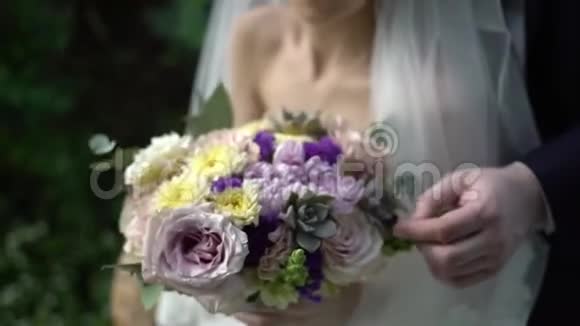 新娘手里的婚礼花束不错新娘和新郎的双手戴着戒指放在一束漂亮的婚礼花束上视频的预览图