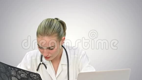 年轻的女医生检查x射线在白色背景下写下对笔记本电脑的诊断结果视频的预览图