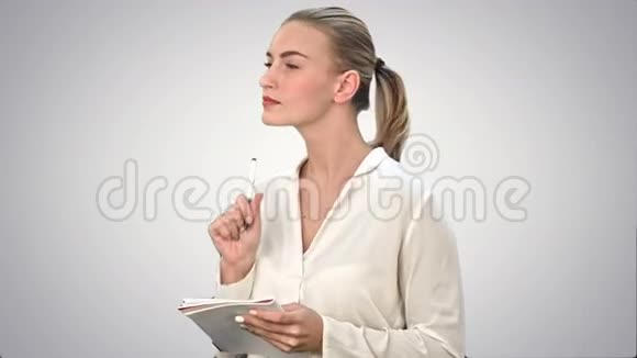 年轻的商务女性发明创意写下直到白色背景的笔记本视频的预览图