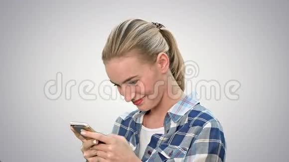 年轻女子微笑着在白色背景下通过手机发短信视频的预览图