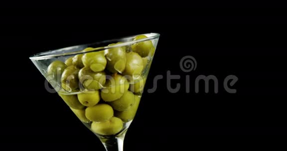 鸡尾酒倒入满是橄榄的玻璃杯中视频的预览图
