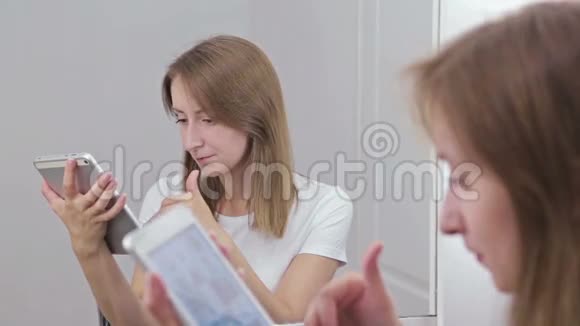 坐在镜子前的女人用数码平板电脑视频的预览图