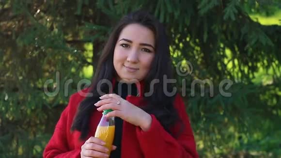 穿红色外套喝橙汁的女孩视频的预览图