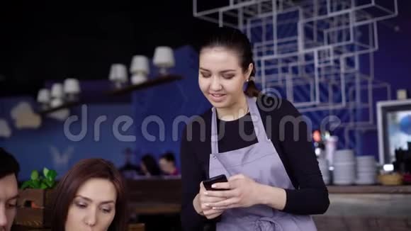 一个穿围裙的侍者女孩接受了三个黑发朋友的点菜他们坐在餐馆里选择视频的预览图