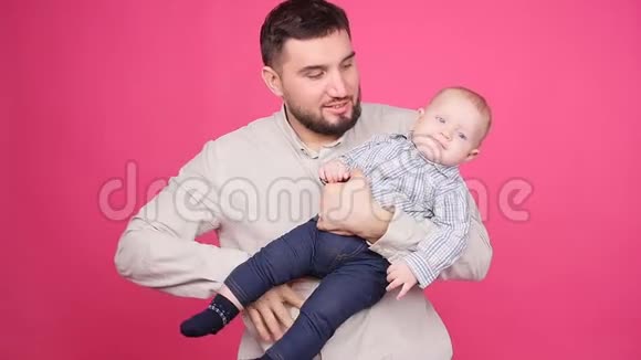 父亲带着可爱的小儿子粉红色的背景视频的预览图