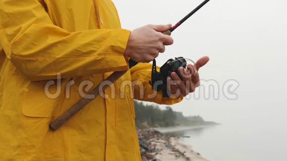 把穿黄色雨衣的渔夫关起来旋转着鱼卷慢动作视频的预览图