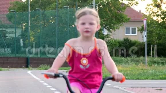 女孩在操场上骑自行车交通夏天骑自行车的小女孩慢速和反向运动视频的预览图