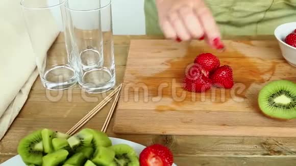 水果鸡尾酒的小板上有香蕉草莓桃子一个女人从盘子里拿出一个草莓放在盘子上视频的预览图