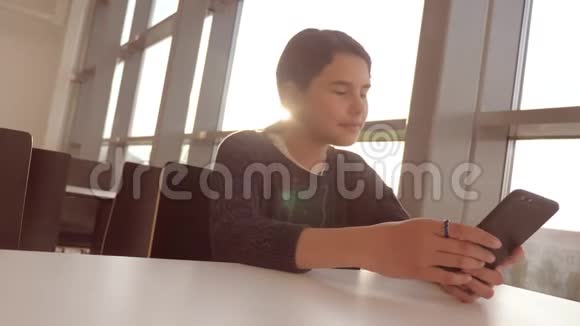 十几岁的女孩正在聊天在一张桌子上的一家咖啡馆里用智能手机传达生活方式视频的预览图