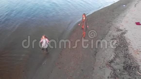 妈妈和女儿快跑在河边的海滩上和一只棕色的狗拉布拉多玩空中拍摄视频的预览图