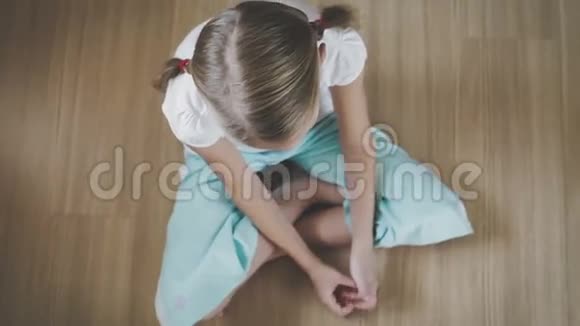 一个悲伤的小女孩坐在家里的地板上视频的预览图