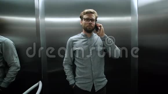 年轻人站在电梯里拿着手机挨着耳朵视频的预览图