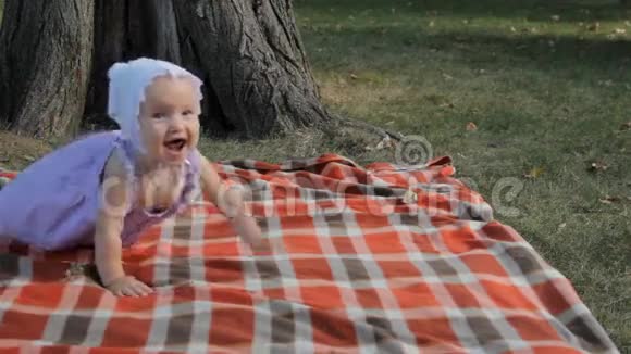 一个小女孩微笑着爬在毯子上视频的预览图