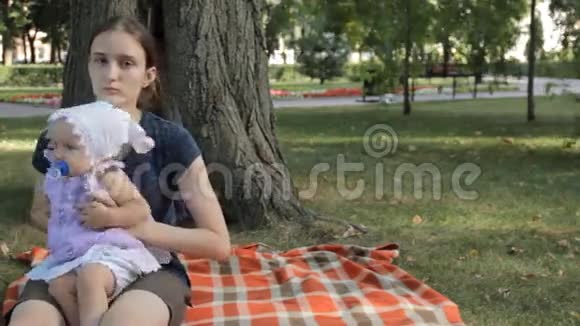 一个年轻的保姆把一个小女孩放在毯子上小女孩爬走了视频的预览图