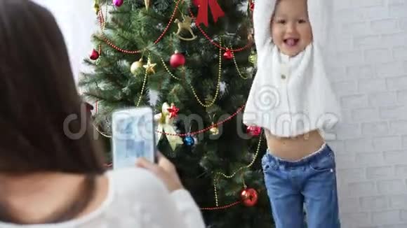 快乐的小女孩在圣诞树附近跳舞和玩猿视频的预览图