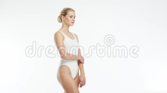 年轻美丽健康和自然的金发女人穿白色泳衣涂上保湿霜按摩护肤视频的预览图