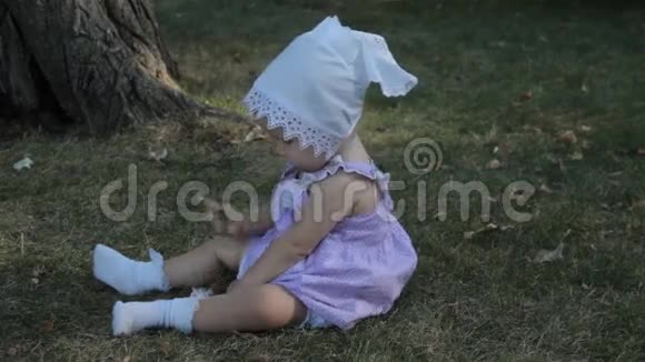 一个戴着帽子的女婴坐在草地上流泪视频的预览图