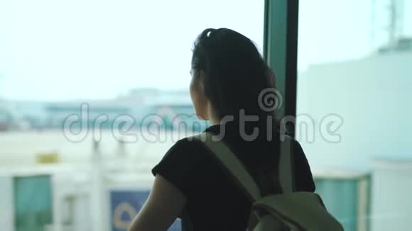 站在机场候机楼窗口的旅行女孩视频的预览图