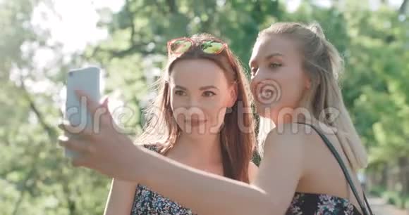 两个年轻快乐的女孩在户外玩和自拍的肖像视频的预览图